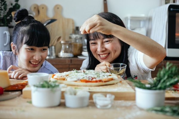 Jak zrobić pizzę? - dwie kobiety w kuchni przygotowujące pizzę