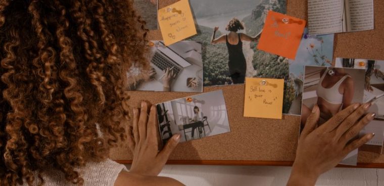 kobieta przypina na tablicy korkowej motywujące cytaty po angielsku